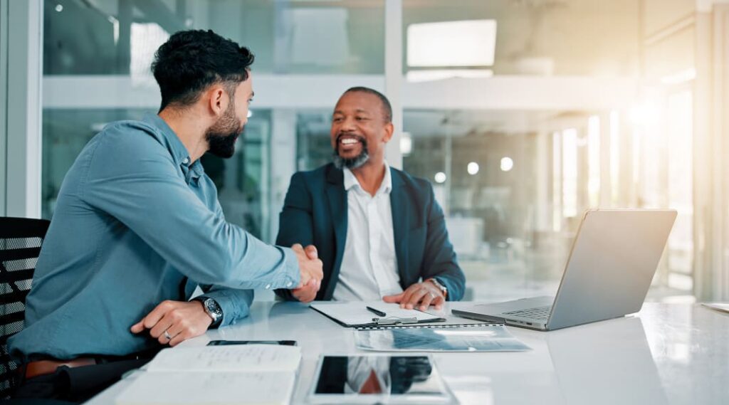 Webdesign Agentur - Zwei Geschäftsleute geben sich nach erfolgreicher Webdesign-Zusammenarbeit die Hand im modernen Büro